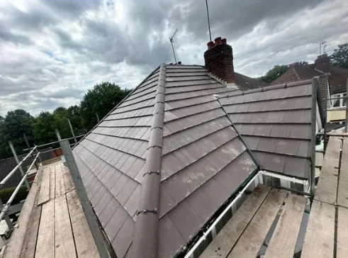 Completed grey tiled hipped roof with scaffolding
